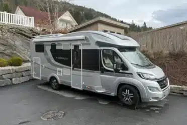 Camping-car gris stationné près d’une maison